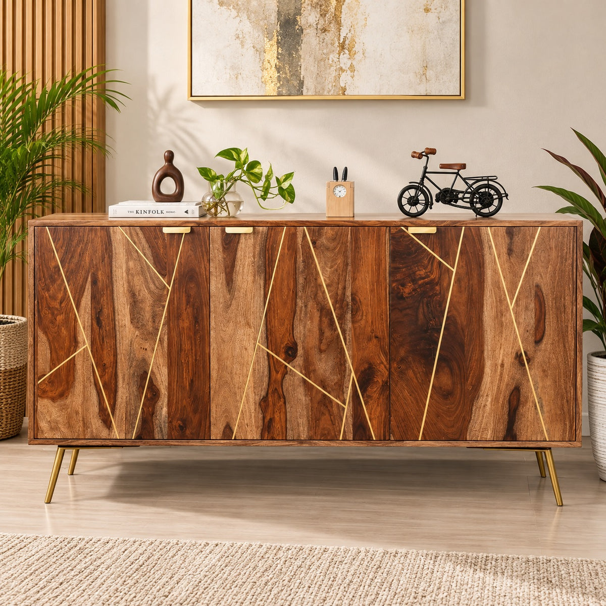 A mid-century modern wooden sideboard cabinet with geometric gold inlay on the doors, styled in a warm, decorated room with plants, books, and a small bicycle decor piece.