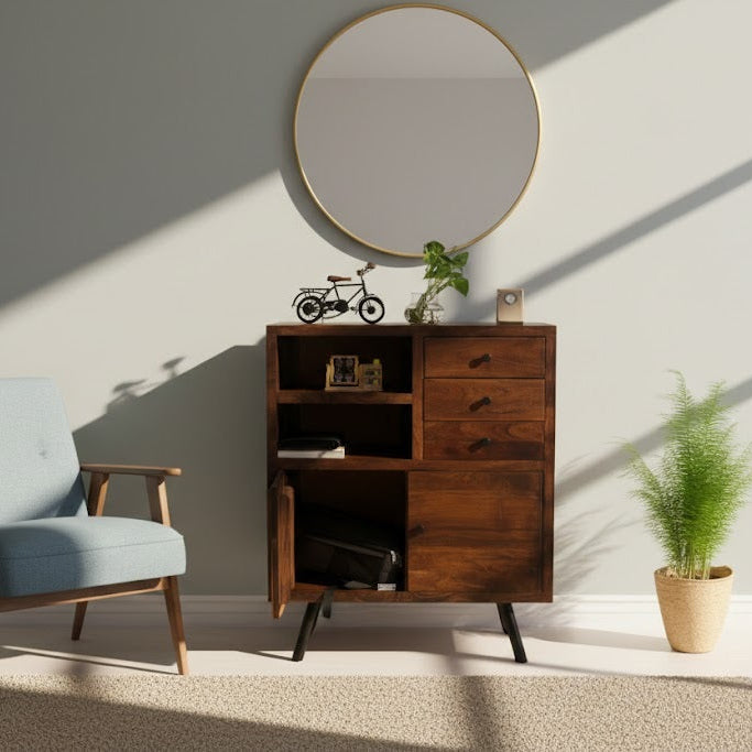 Wooden cabinet with a round mirror above it in a room with a blue armchair and a plant.